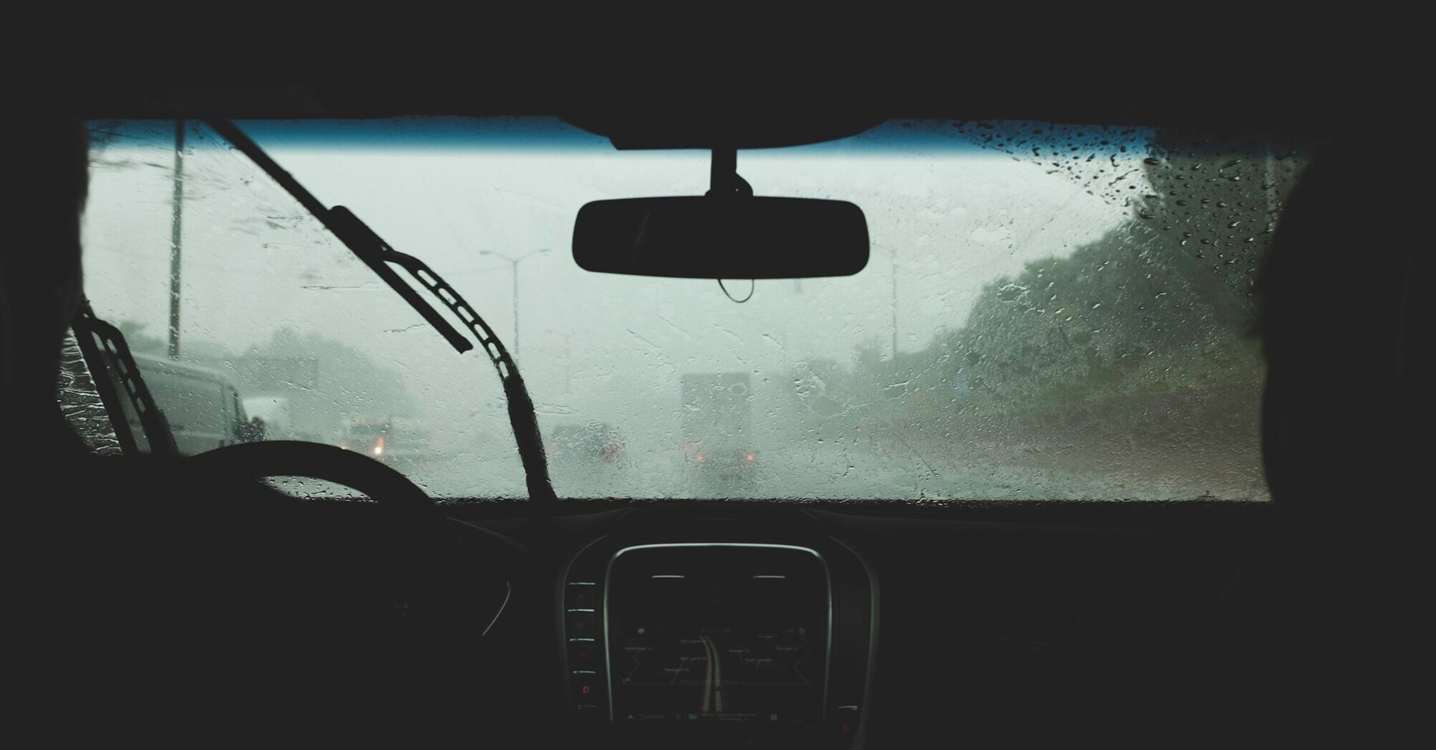 View from inside a car during heavy rain, with blurred visibility through the windshield