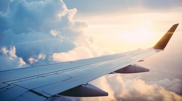 Airplane wing against a backdrop of clouds during sunrise or sunset