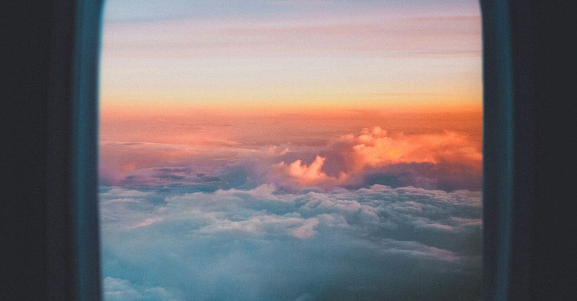 A scenic view of colorful clouds and a sunset seen through an airplane window