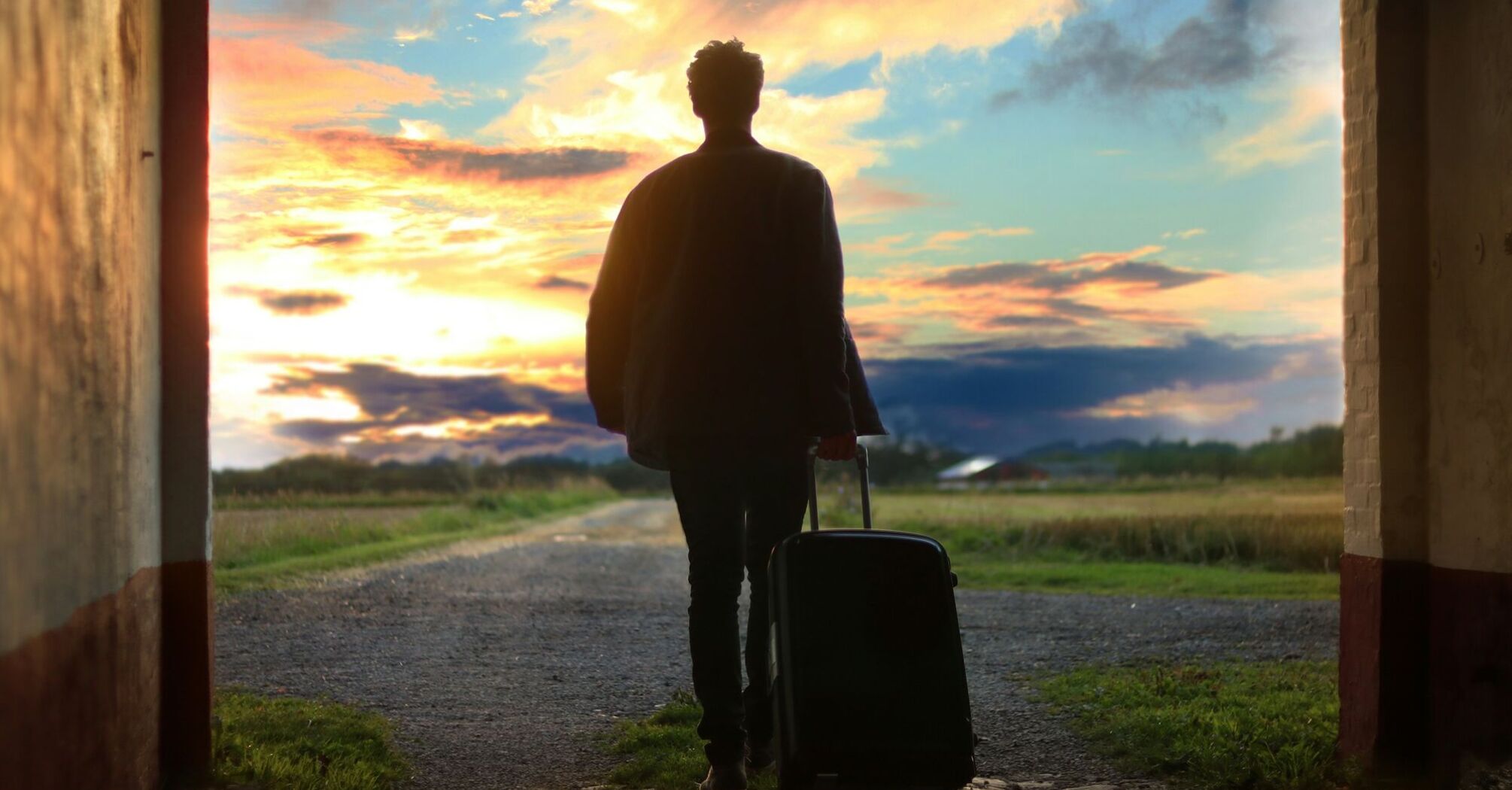 A traveler with a suitcase walking towards a scenic sunset, symbolizing exploration and new adventures