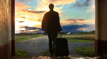 A traveler with a suitcase walking towards a scenic sunset, symbolizing exploration and new adventures