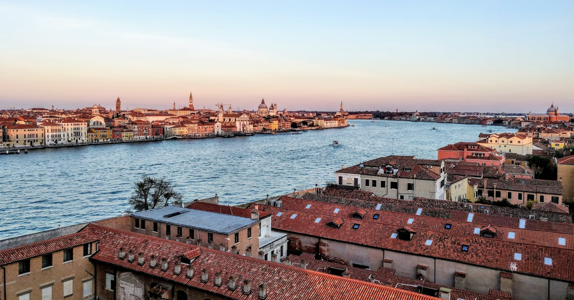 A panoramic view of Venice at sunset with historic buildings and canals visible