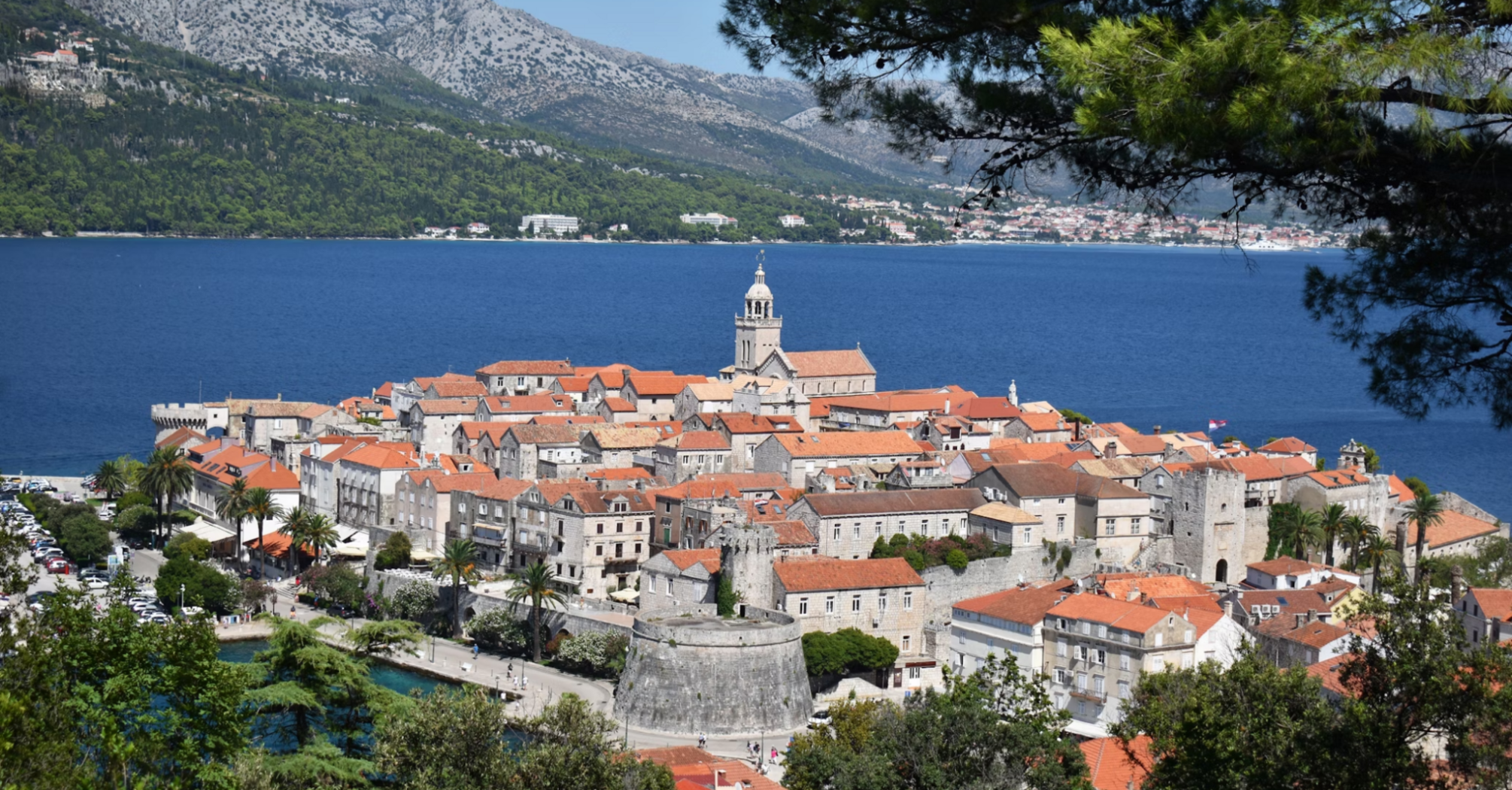 A scenic view of Korčula town with its historic architecture and red-tiled roofs surrounded by the Adriatic Sea