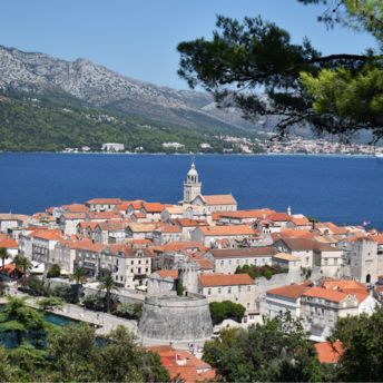 A scenic view of Korčula town with its historic architecture and red-tiled roofs surrounded by the Adriatic Sea