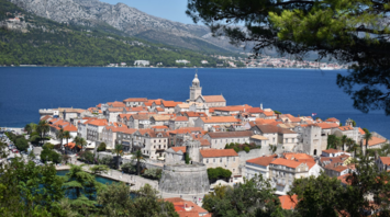 A scenic view of Korčula town with its historic architecture and red-tiled roofs surrounded by the Adriatic Sea