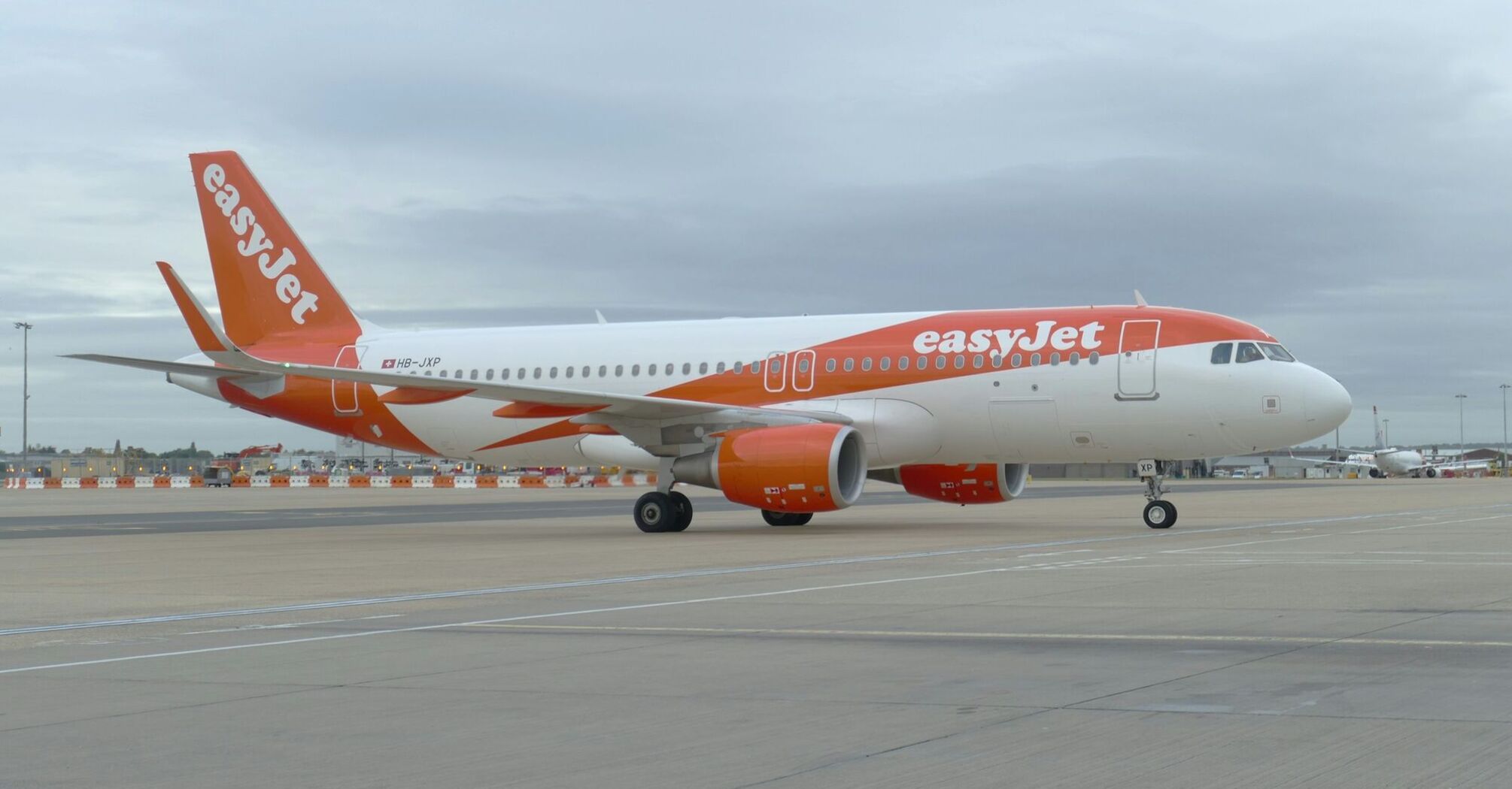 easyJet Airbus A320 parked at the airport tarmac under cloudy skies