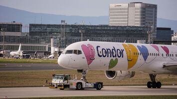 Condor airplane with colorful heart-themed livery being towed at an airport terminal
