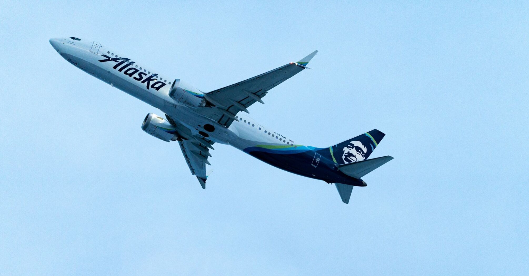 Alaska Airlines plane flying against a clear blue sky