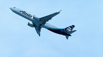 Alaska Airlines plane flying against a clear blue sky