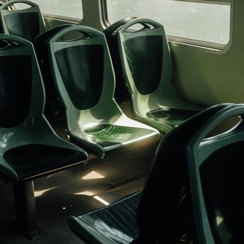 Empty green seats inside a public transport vehicle illuminated by sunlight through the windows