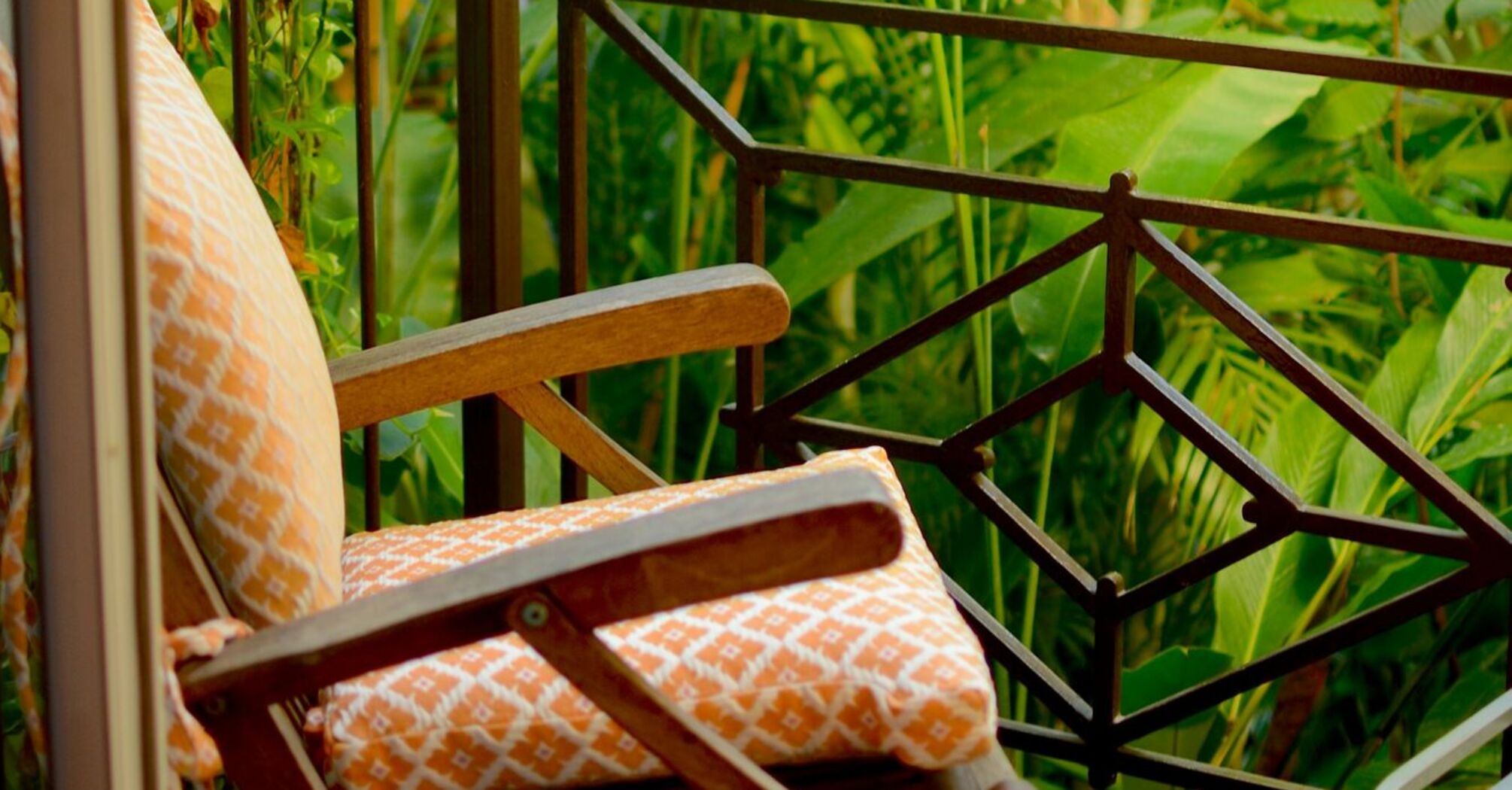 A cozy chair on a balcony surrounded by lush green tropical plants