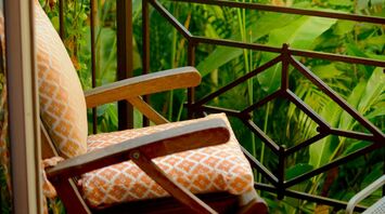 A cozy chair on a balcony surrounded by lush green tropical plants
