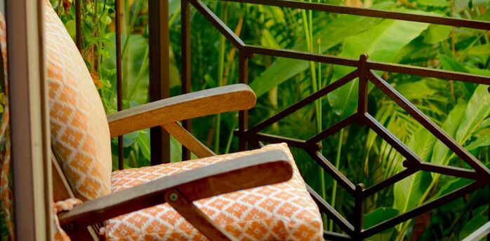 A cozy chair on a balcony surrounded by lush green tropical plants