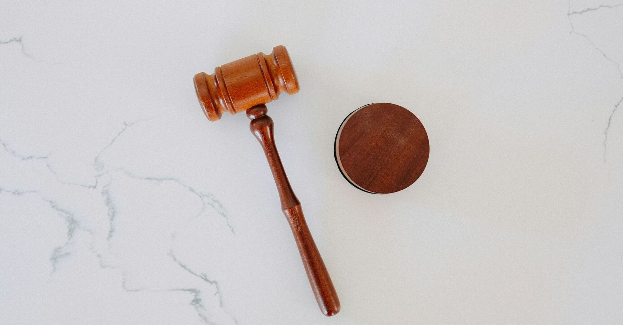 A wooden judge's gavel resting on a white marble surface