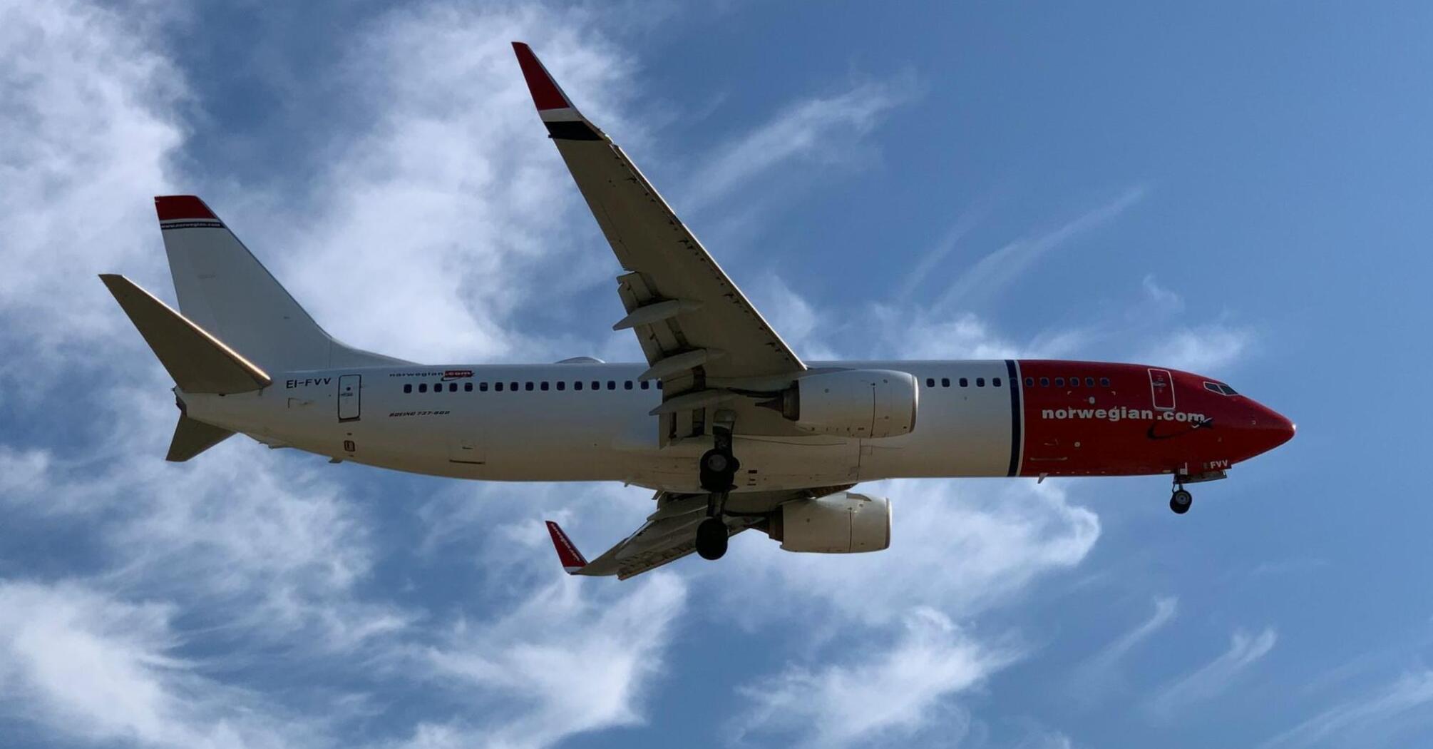 Norwegian aircraft approaching for landing under clear blue sky