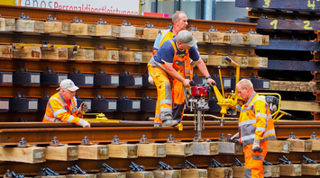 Workers in high-visibility clothing installing and maintaining railway tracks