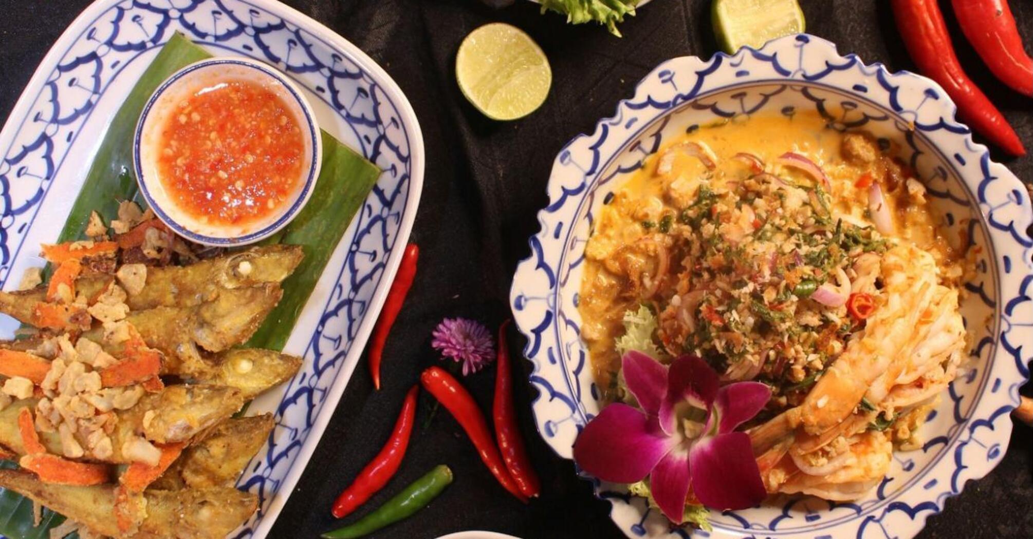 Traditional Thai dishes with herbs, spices, and sauces arranged on decorative plates