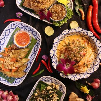 Traditional Thai dishes with herbs, spices, and sauces arranged on decorative plates