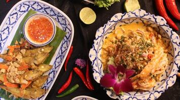 Traditional Thai dishes with herbs, spices, and sauces arranged on decorative plates