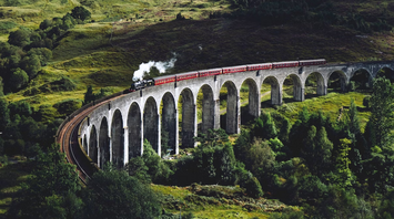 Steam train crossing a scenic viaduct in the Scottish Highlands
