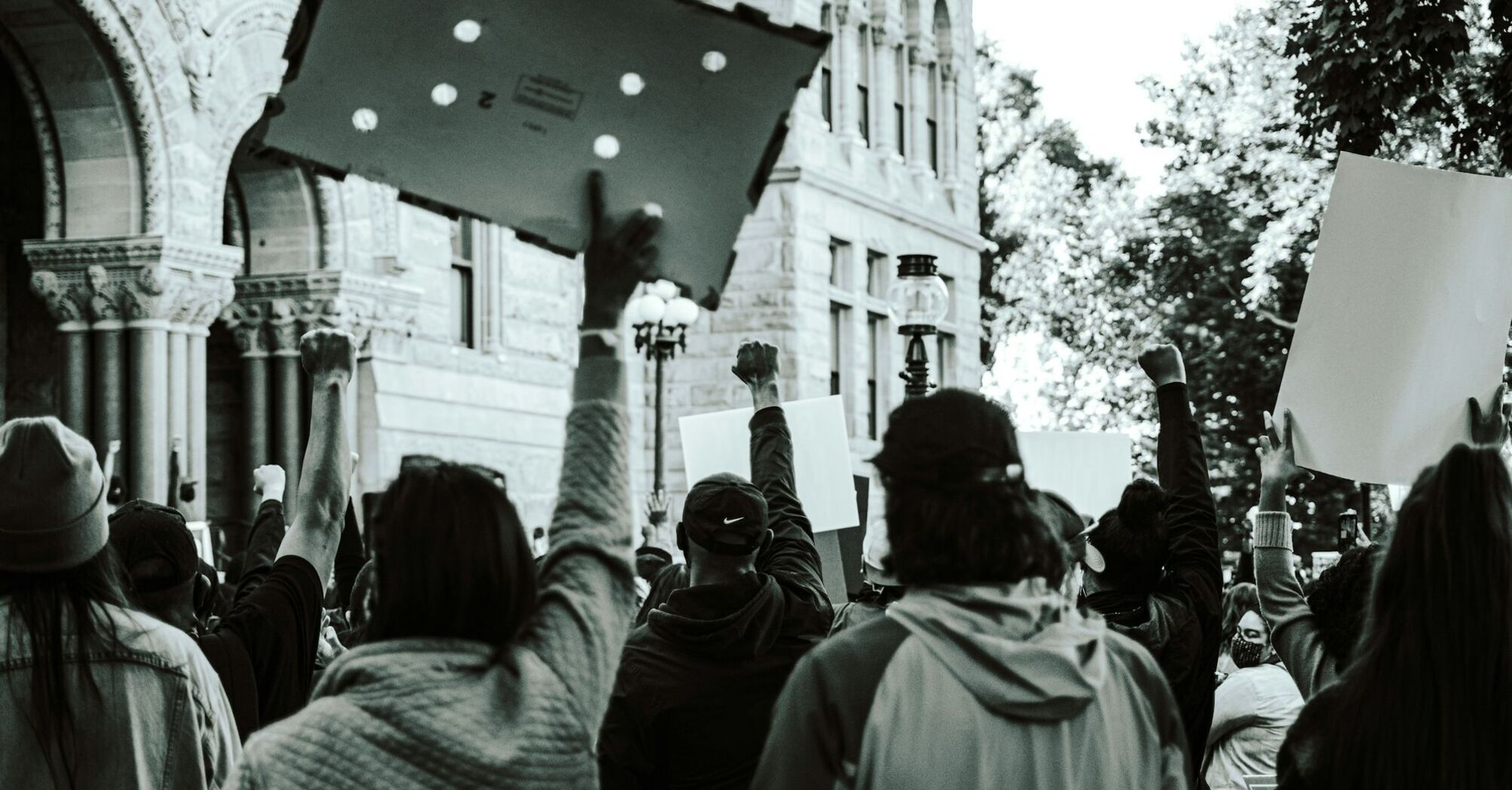 Protesters holding placards during a public demonstration in an urban area