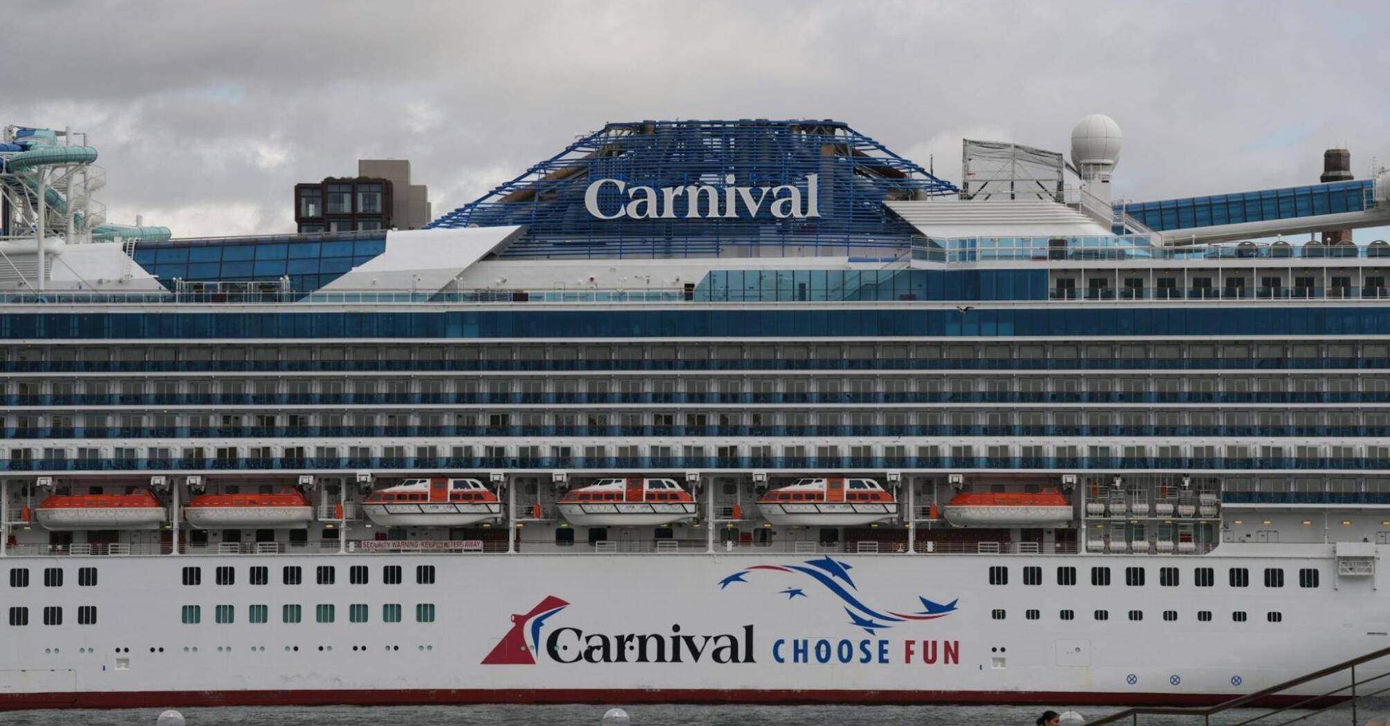 Carnival cruise ship docked at a port with passengers walking nearby