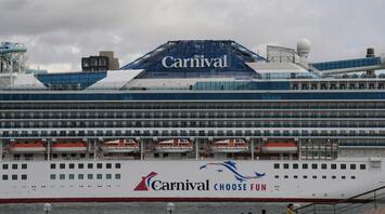 Carnival cruise ship docked at a port with passengers walking nearby