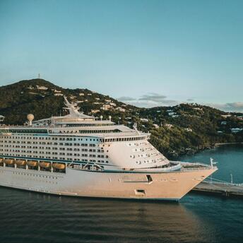 Cruise ship docked at a Caribbean island port during sunset