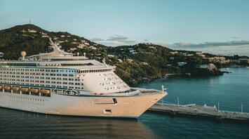 Cruise ship docked at a Caribbean island port during sunset