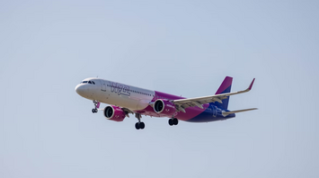 A Wizz Air aircraft approaching for landing against a clear sky