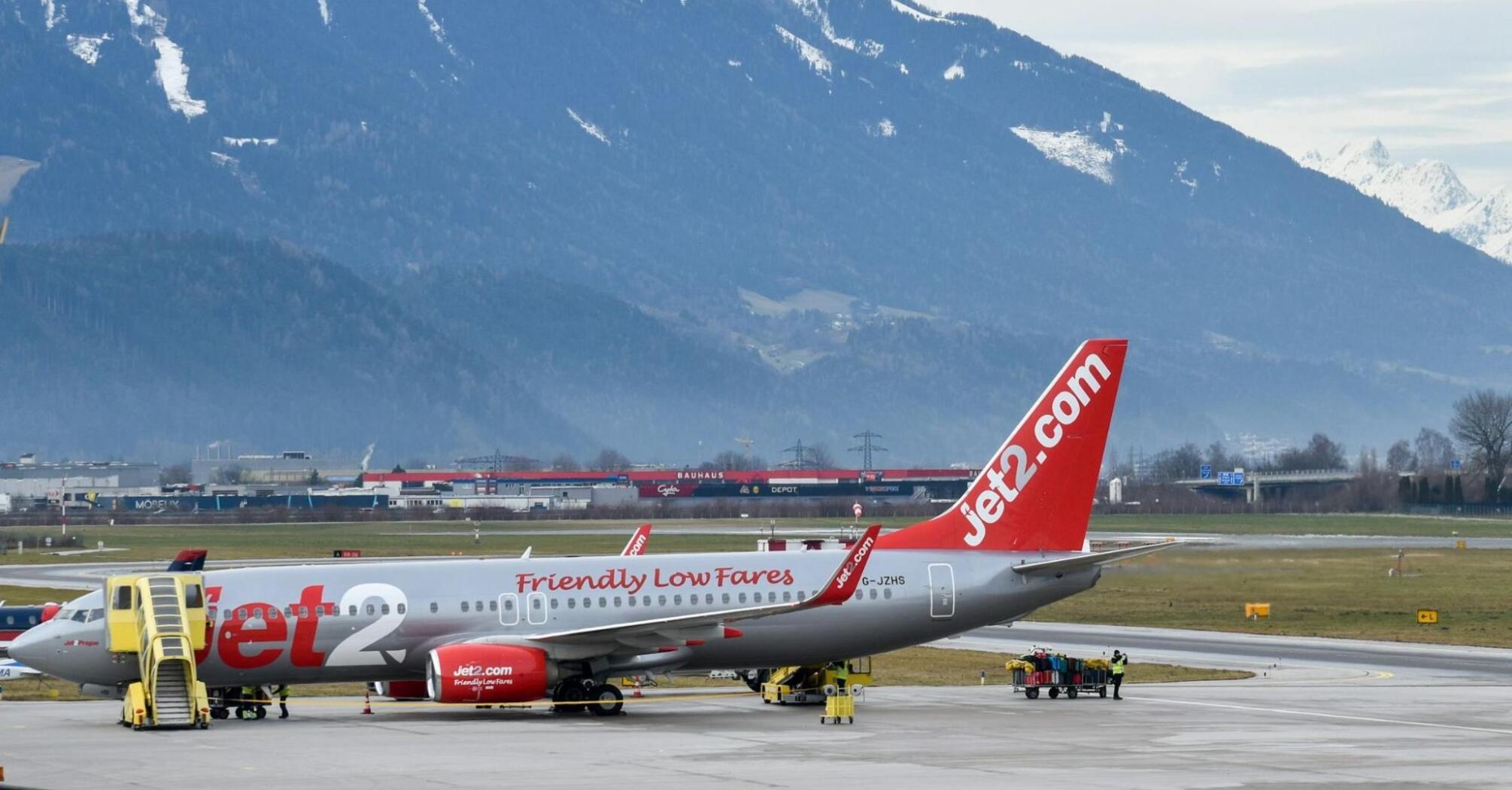 Jet2 aircraft parked at an airport with snow-capped mountains in the background
