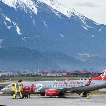 Jet2 aircraft parked at an airport with snow-capped mountains in the background