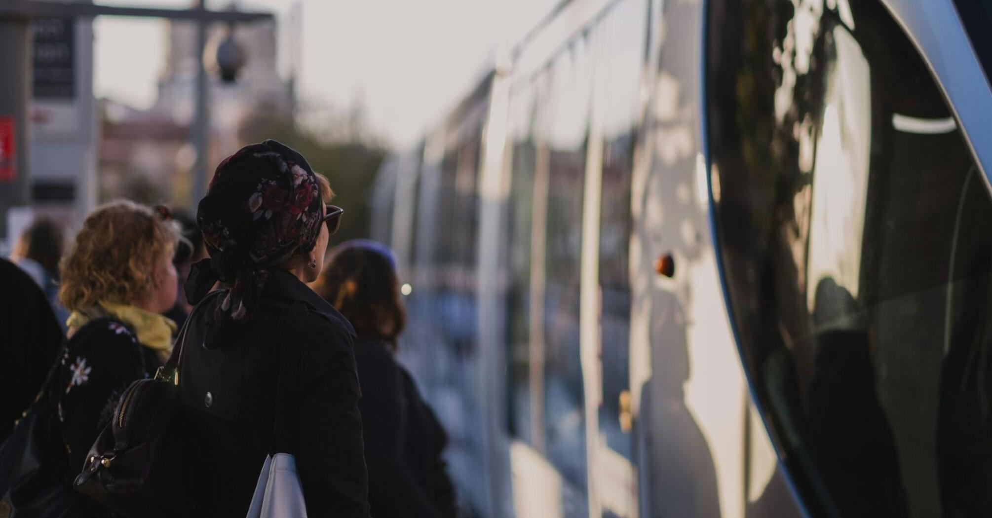 People waiting to board a public bus at sunset