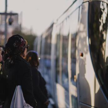 People waiting to board a public bus at sunset