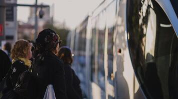 People waiting to board a public bus at sunset