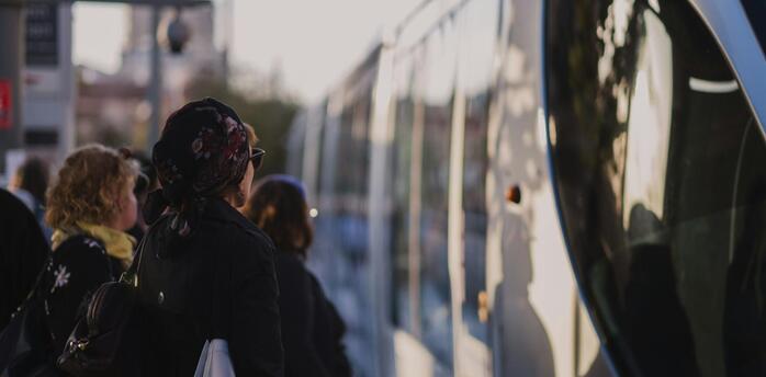 People waiting to board a public bus at sunset