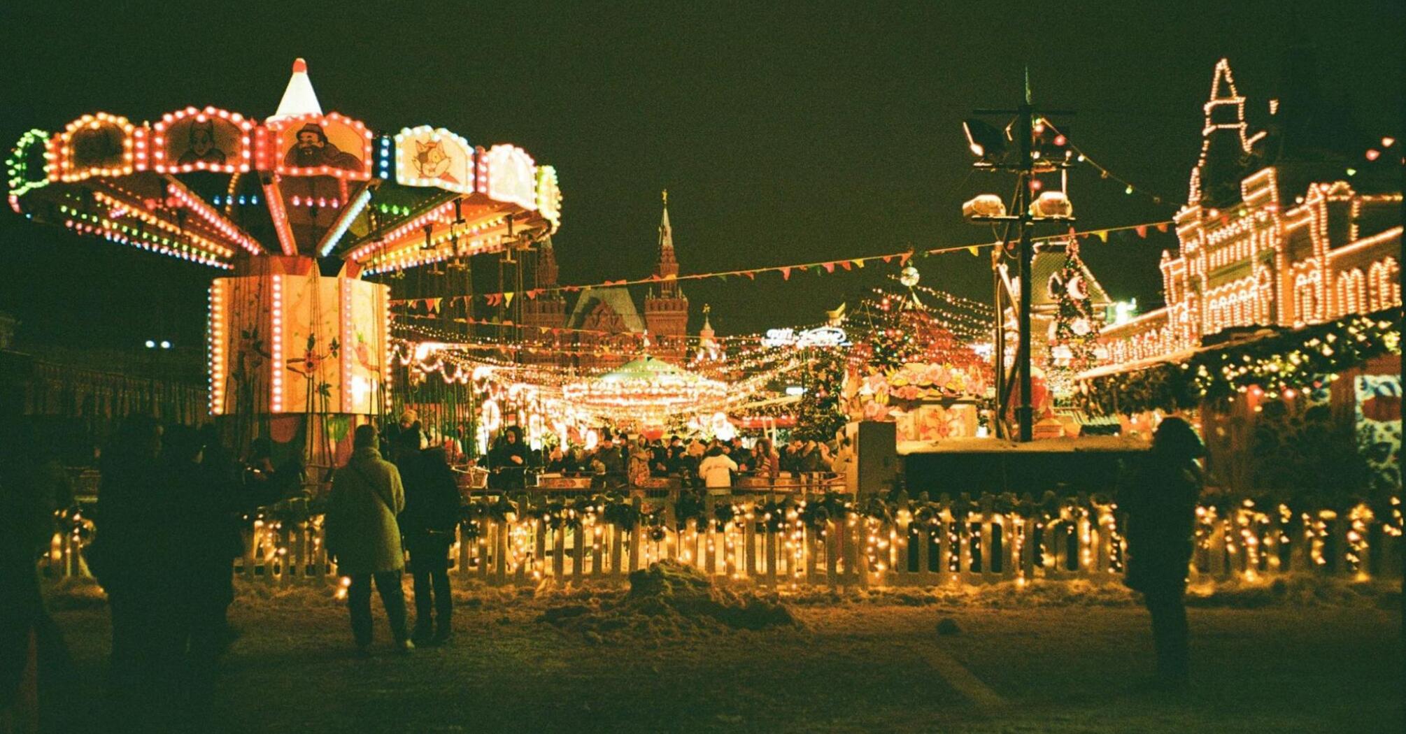 Brightly lit winter fairground with carousel and festive lights at night