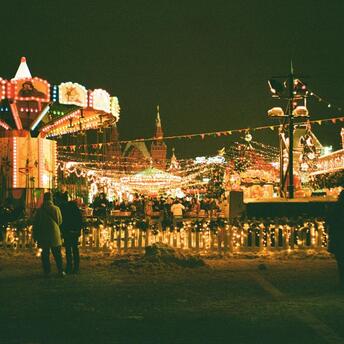 Brightly lit winter fairground with carousel and festive lights at night