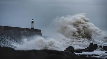 Large waves crash against a lighthouse during a storm