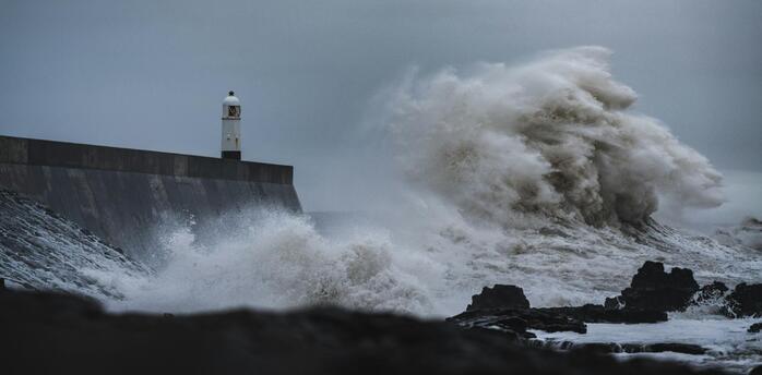 Large waves crash against a lighthouse during a storm