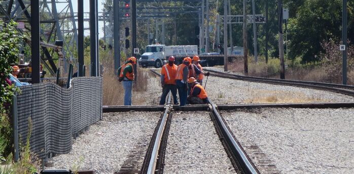 Railway maintenance workers repairing track junction during daylight