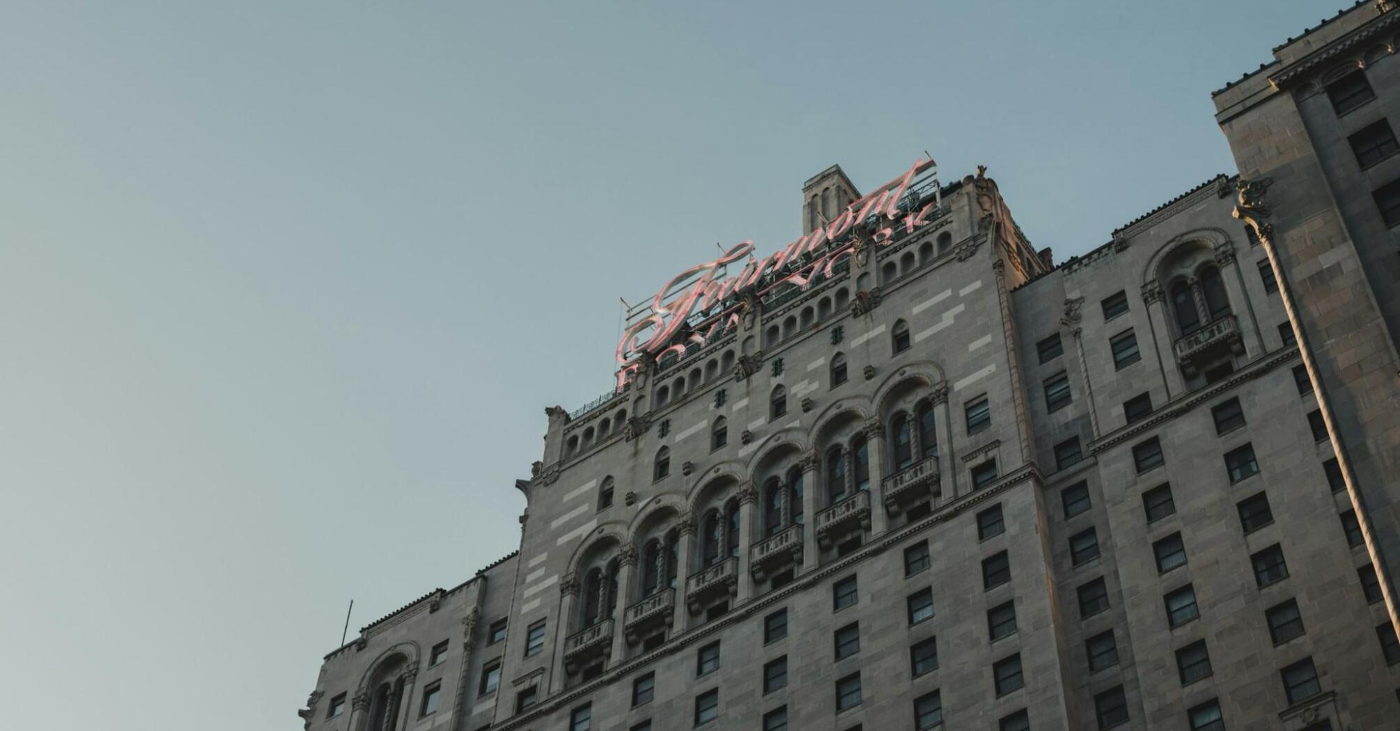 The historic façade of a Fairmont hotel under a clear sky