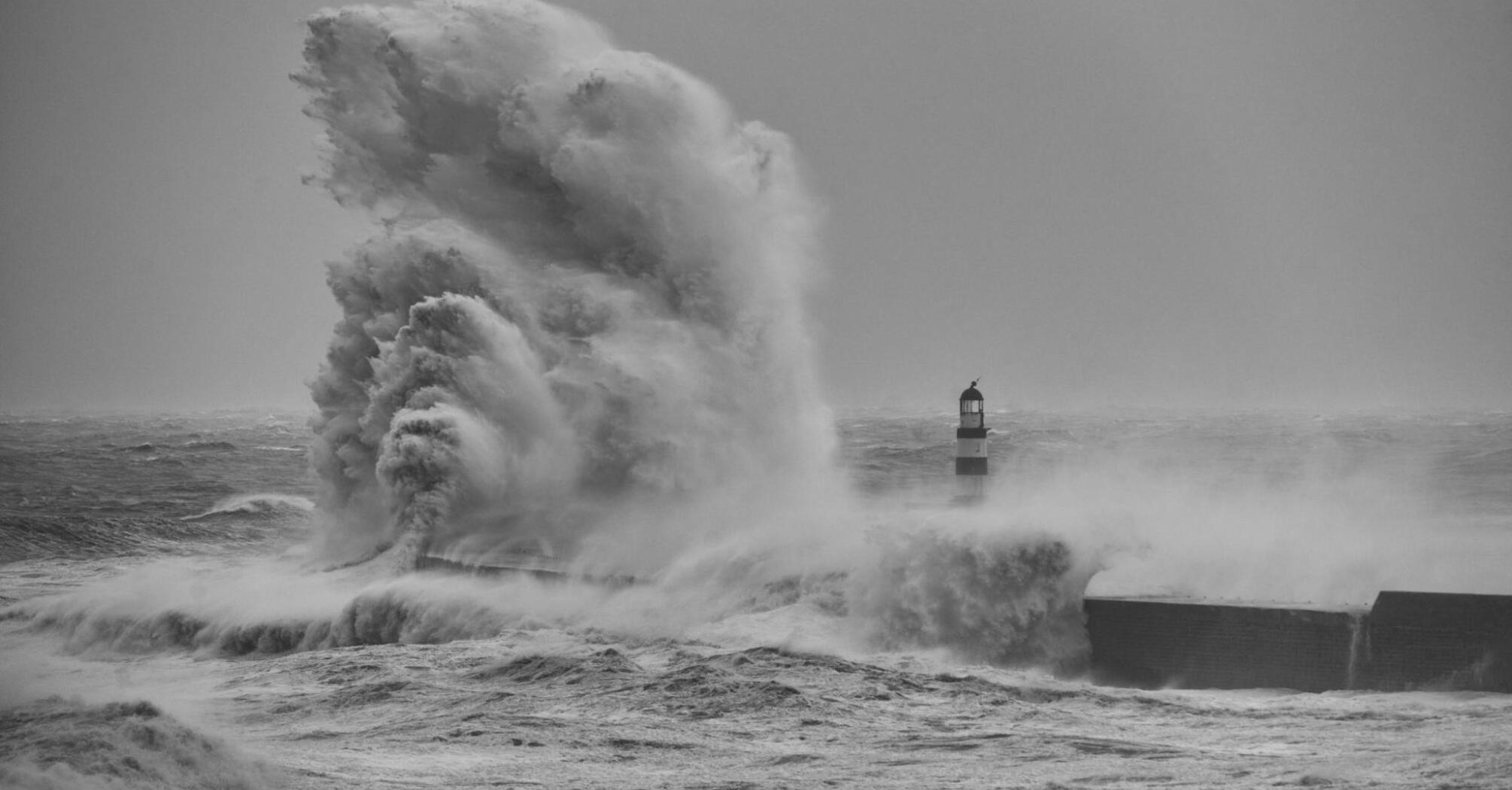 Massive waves crash against a coastal lighthouse during Storm Benjamin