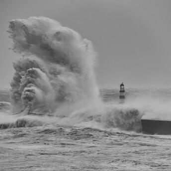 Massive waves crash against a coastal lighthouse during Storm Benjamin