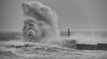 Massive waves crash against a coastal lighthouse during Storm Benjamin