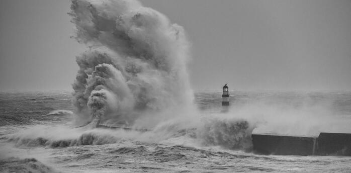 Massive waves crash against a coastal lighthouse during Storm Benjamin
