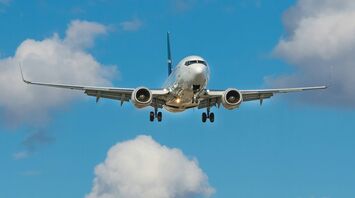 Airplane approaching for landing against a blue sky