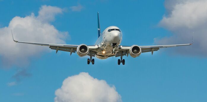 Airplane approaching for landing against a blue sky