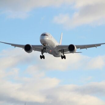 Commercial aircraft preparing to land against a blue sky