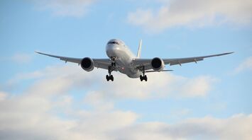 Commercial aircraft preparing to land against a blue sky